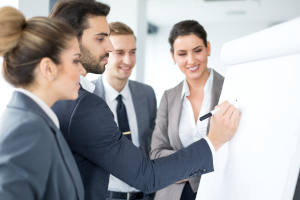 Ein QM Berater plant an einem Flipchart gemeinsam mit einem Team die nächsten Schritte zur Aufsetzung eines neuen Prozesses.